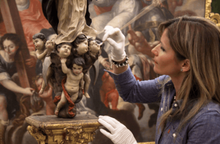 Mujer restaurando la cabeza de un angelito de una escultura de una Virgen.